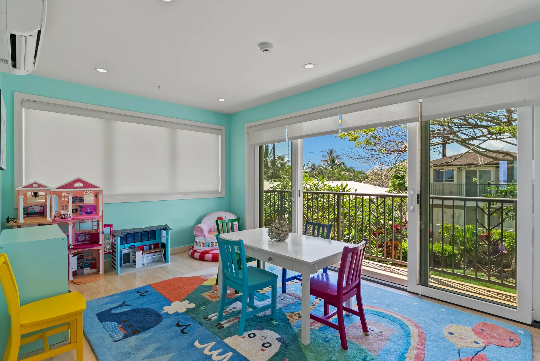 Un cuarto de juegos colorido con una mesa y sillas infantiles junto a puertas corredizas de vidrio.