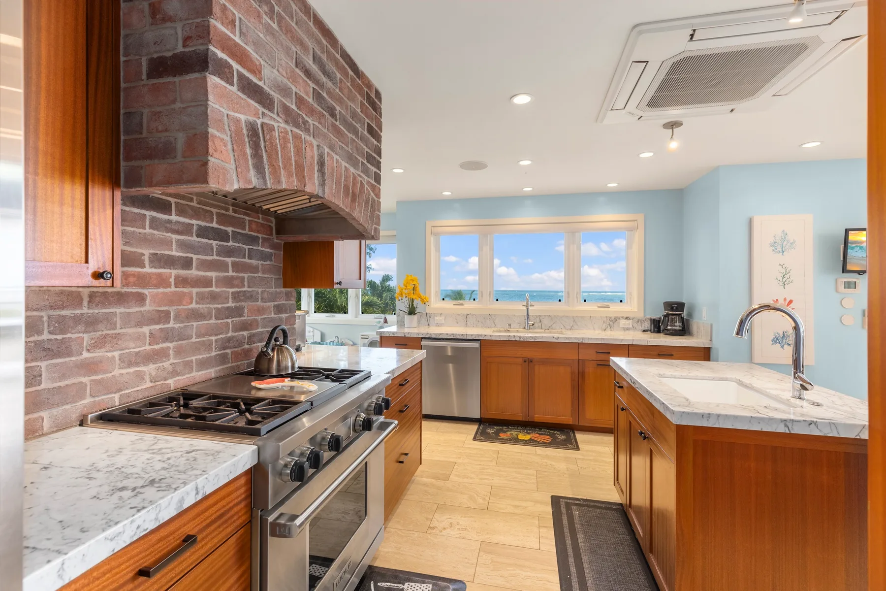 Una cocina luminosa con gabinetes de madera, encimeras de piedra y una ventana grande.
