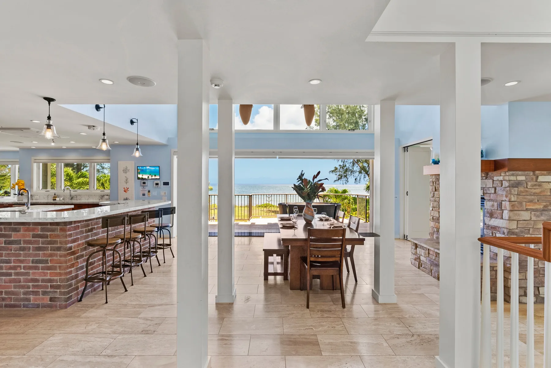 Una zona abierta de comedor y cocina da a grandes ventanales con vistas al agua.