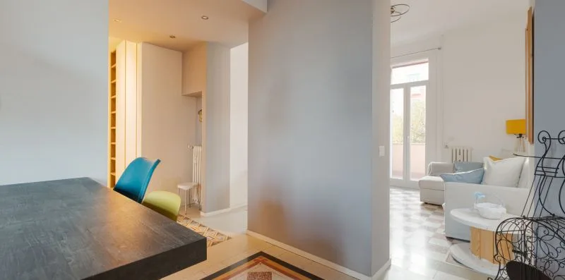 A bright living room with a dining table and seating beside tall windows.