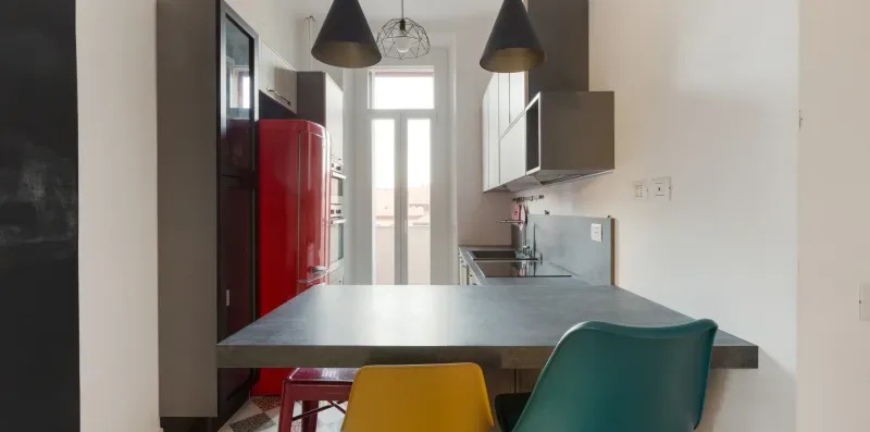 A modern kitchen with a broad island and colorful seating.