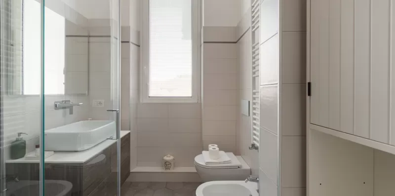 A tiled bathroom with a glass shower and a window.