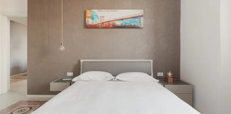 A bedroom with a neatly made bed against a gray accent wall.