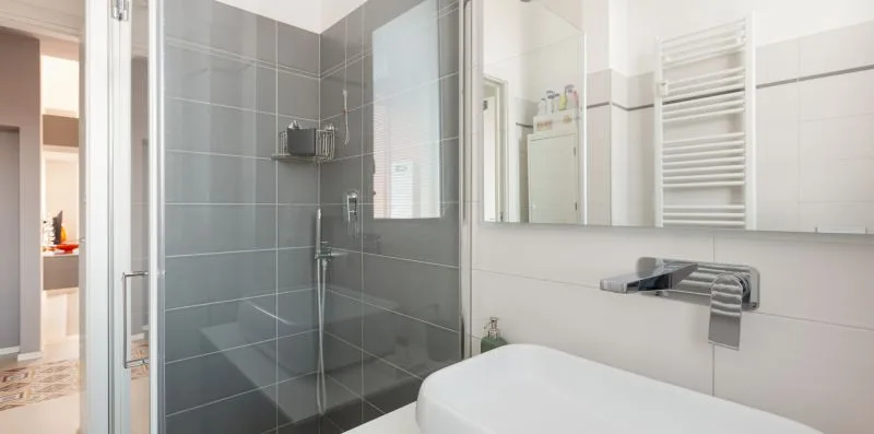 A modern bathroom with a glass shower and a white bathtub.