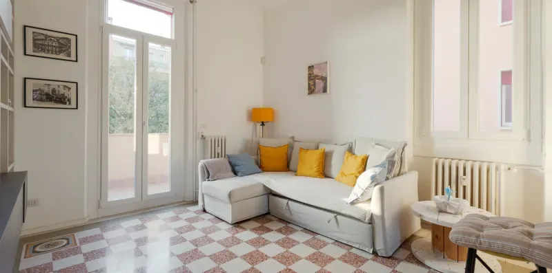 A bright living room with a light-colored sectional and yellow cushions.