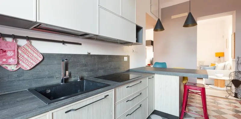 A modern kitchen with a dark countertop and an island opening toward the dining area.