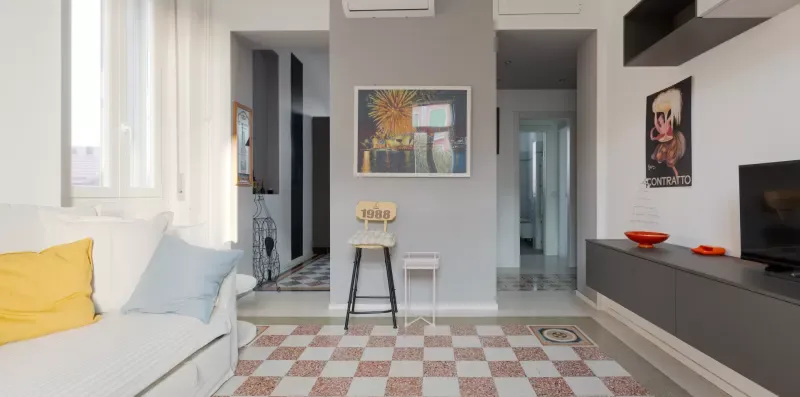 A bright living room with a white sofa, patterned rug, and wall art.