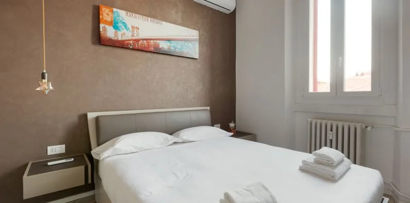 A bedroom with a neatly made bed beneath a colorful wall picture.