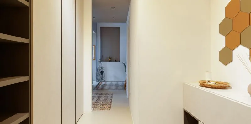 A bright hallway leads to a tiled bathroom, with built-in shelving along one side.