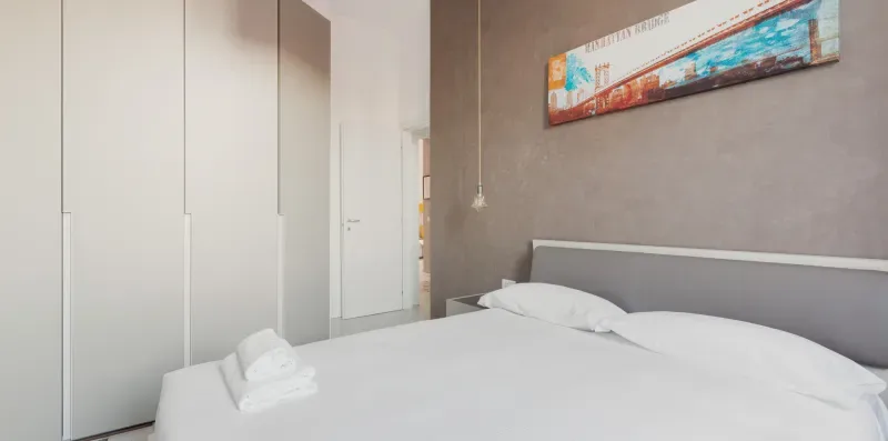 A bedroom with a neatly made bed and colorful artwork on the wall.