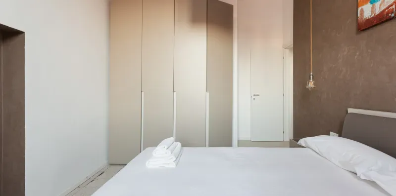 Bedroom with a neatly made bed and built-in wardrobes.