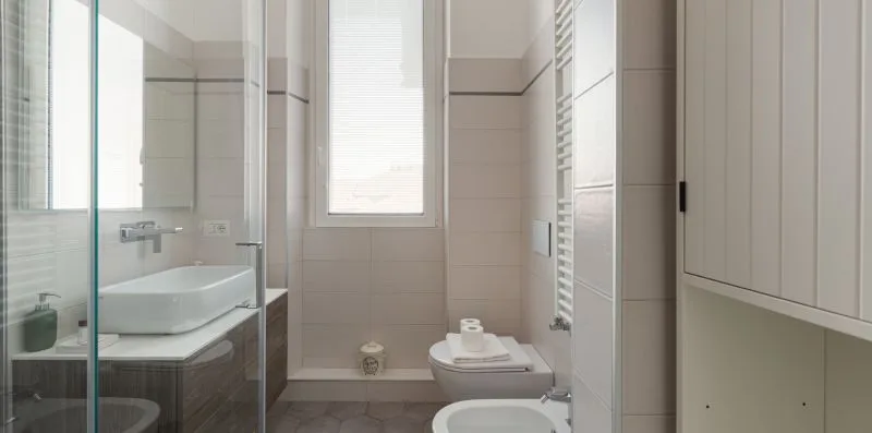 A tiled bathroom with a glass shower, sink, and toilet.