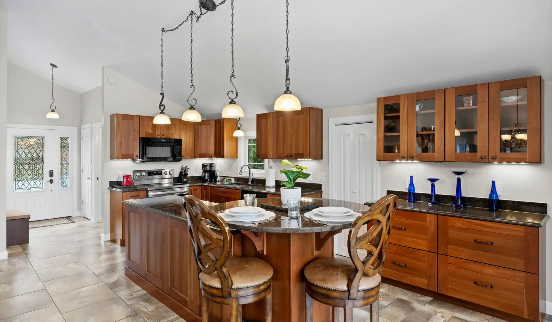 A bright kitchen with a wooden island, dining chairs, and pendant lights.