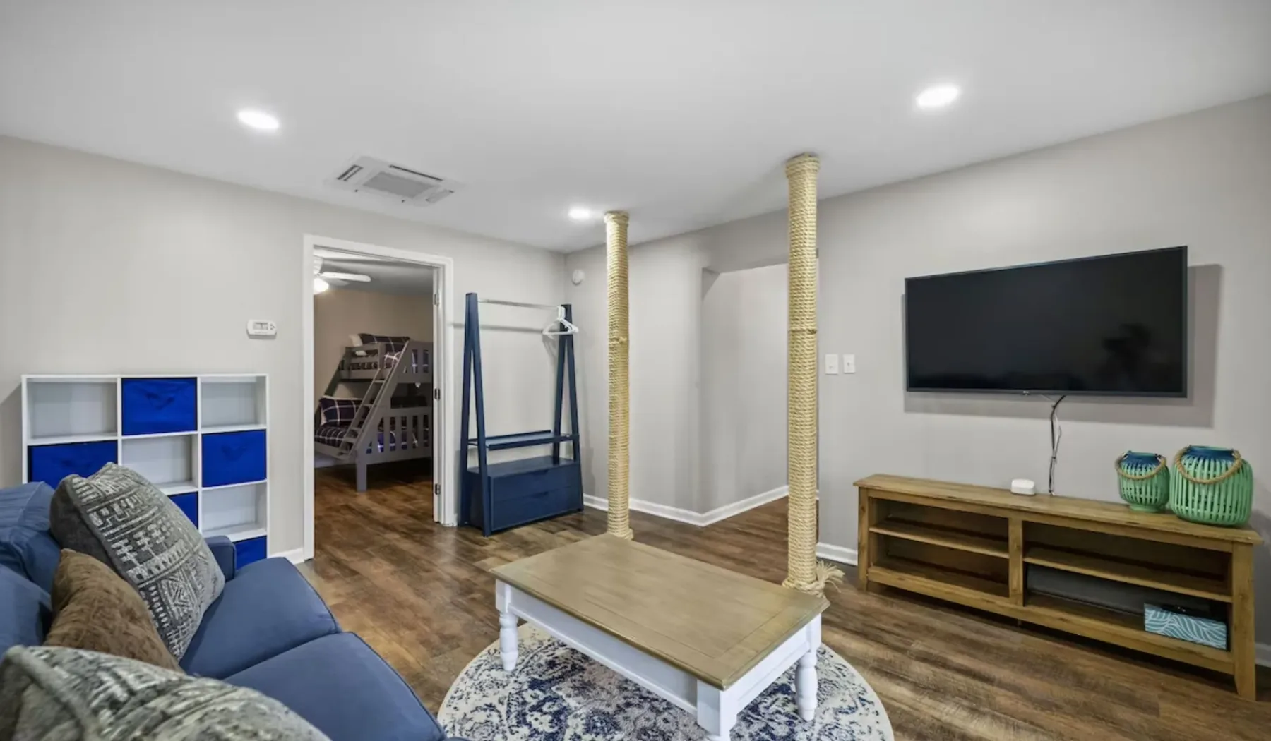 A living room with blue seating, a television, and a low wooden console.
