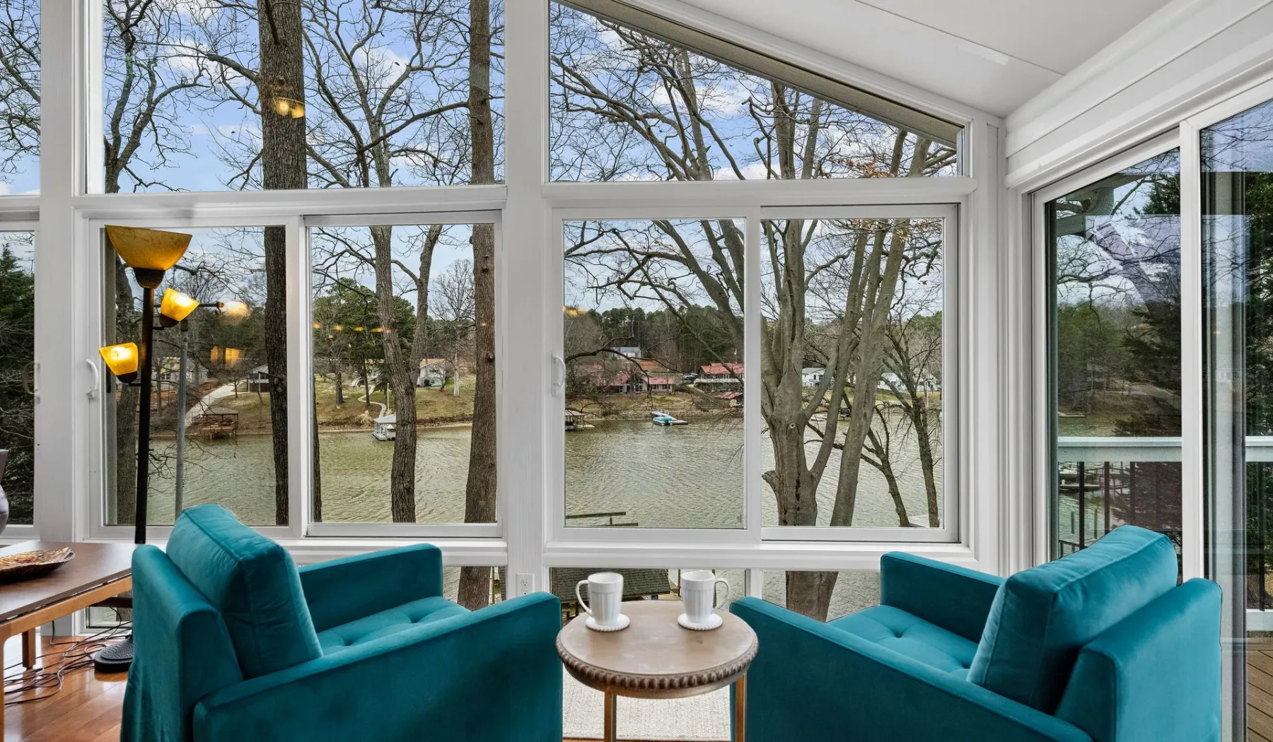 A bright sitting area with teal seating and large windows overlooking the water.