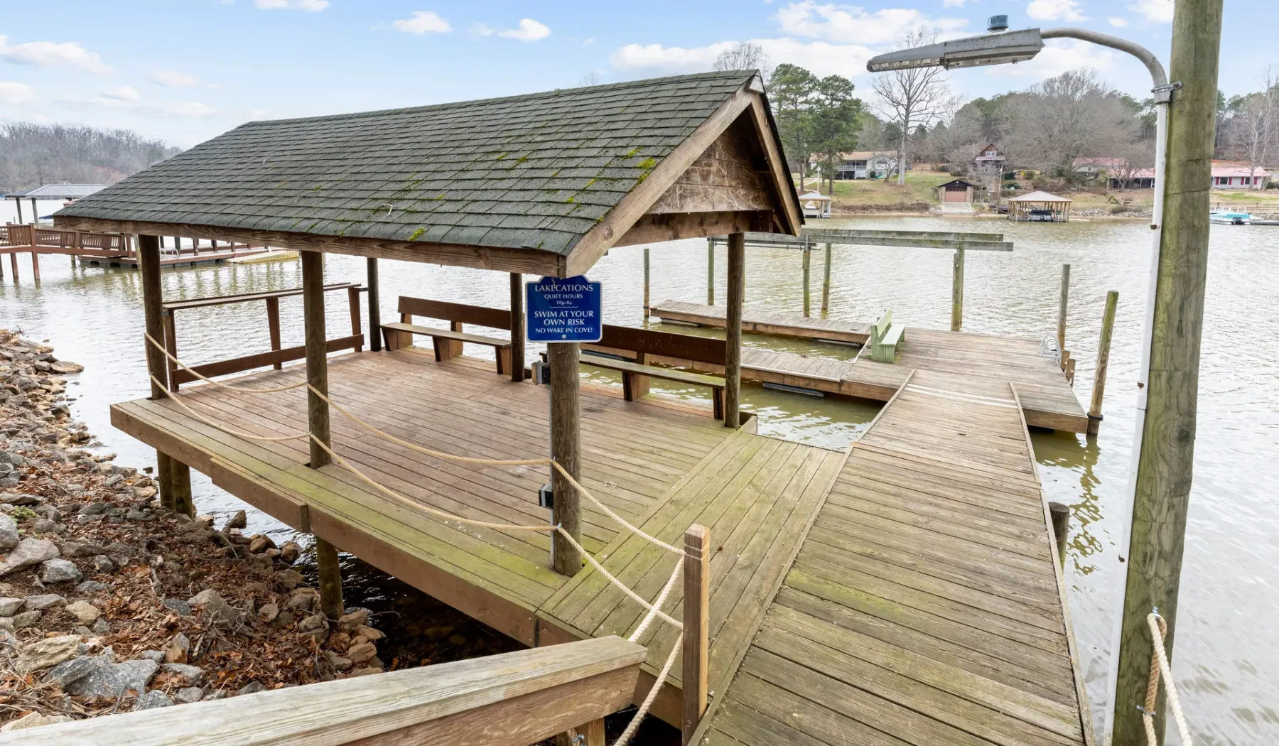 A wooden dock shelter extends over the water, with a covered seating area.