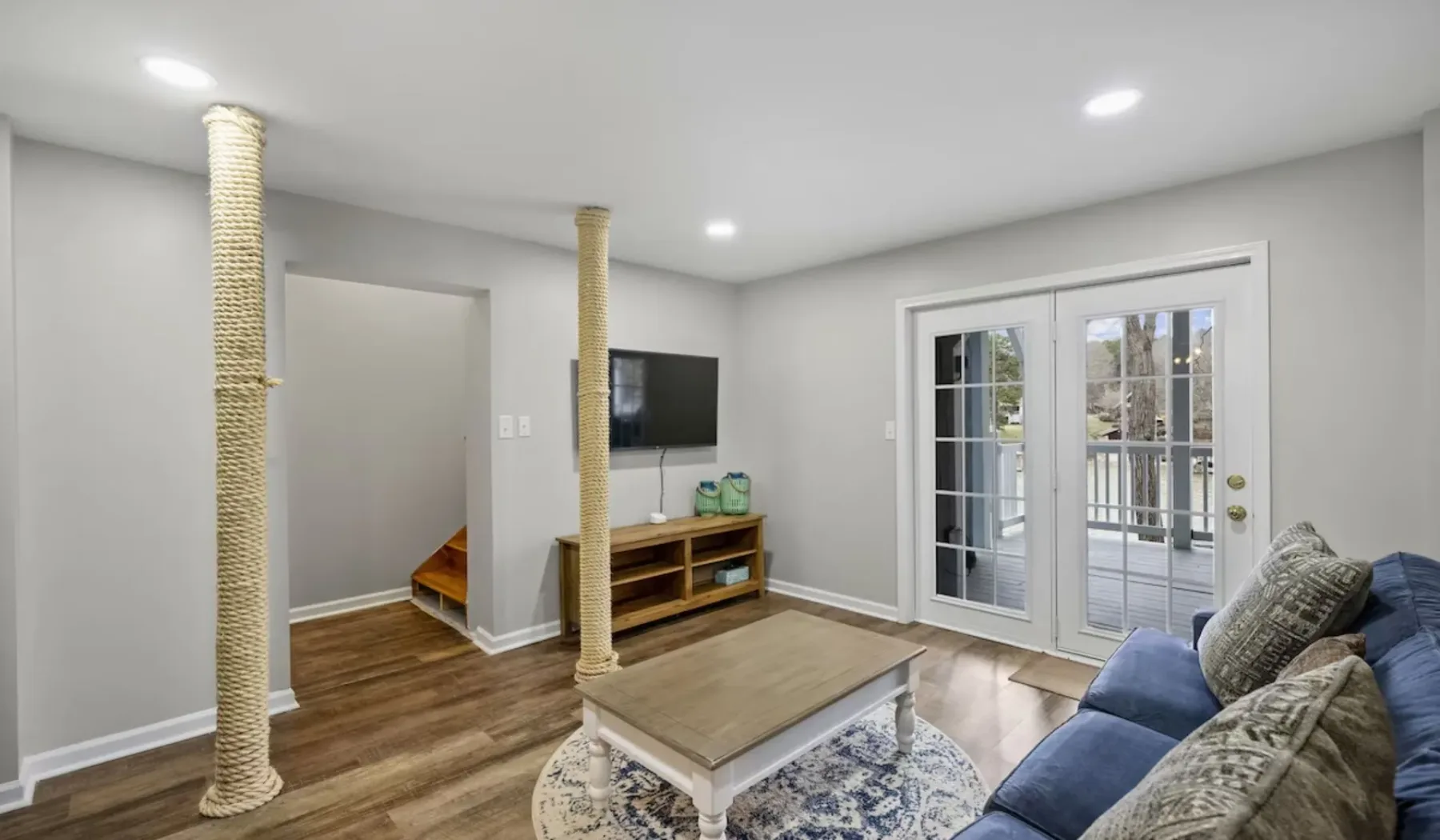 A living room with seating, a television, and glass doors opening to a deck.