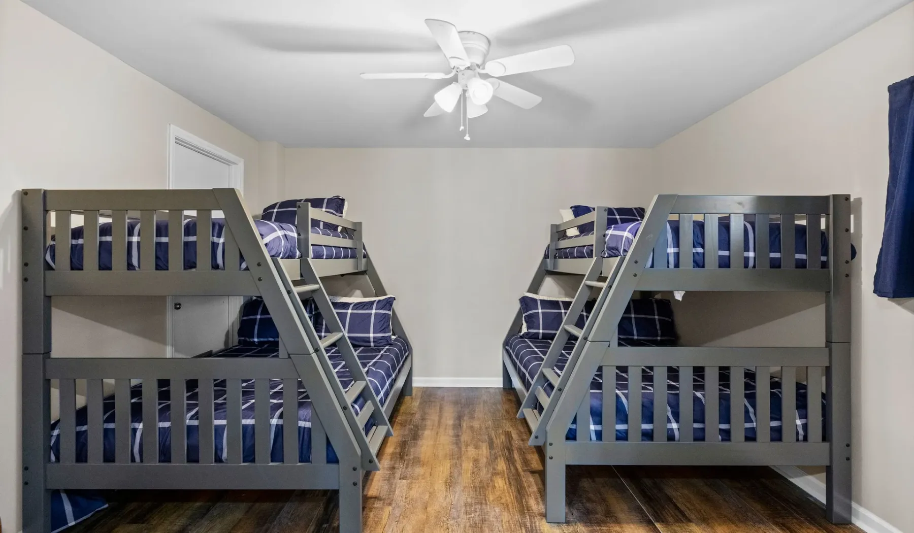 A bedroom with two sets of bunk beds and blue bedding.