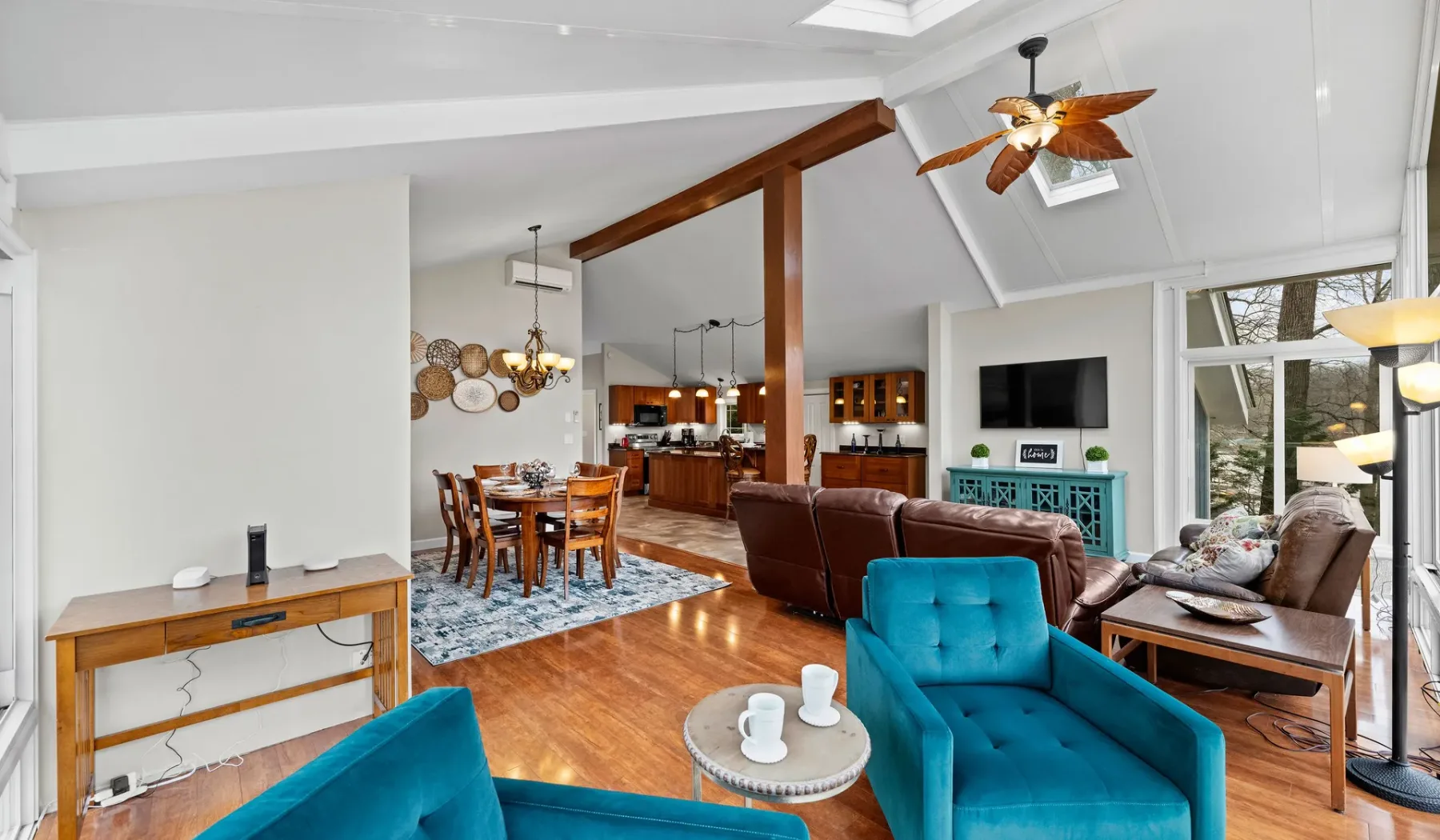 A bright open-plan living and dining room with colorful seating and a wooden floor.