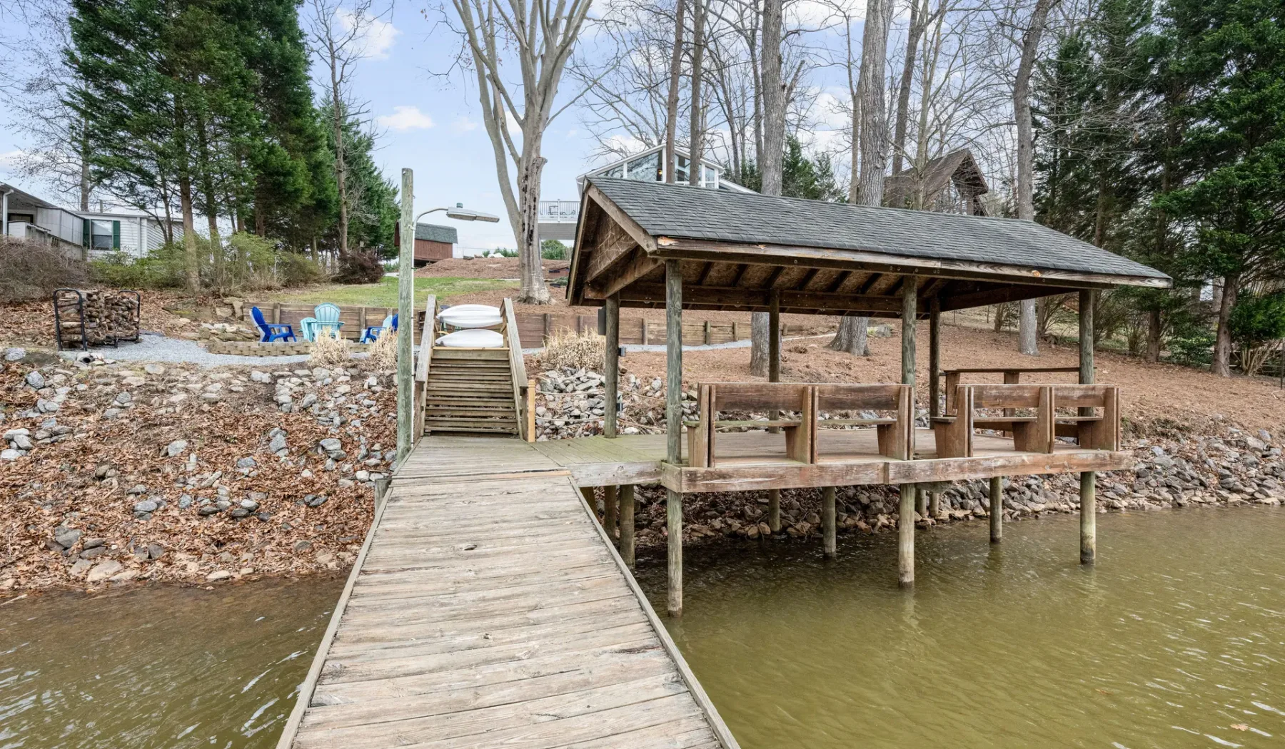 A wooden dock leads to a covered lakeside seating area.