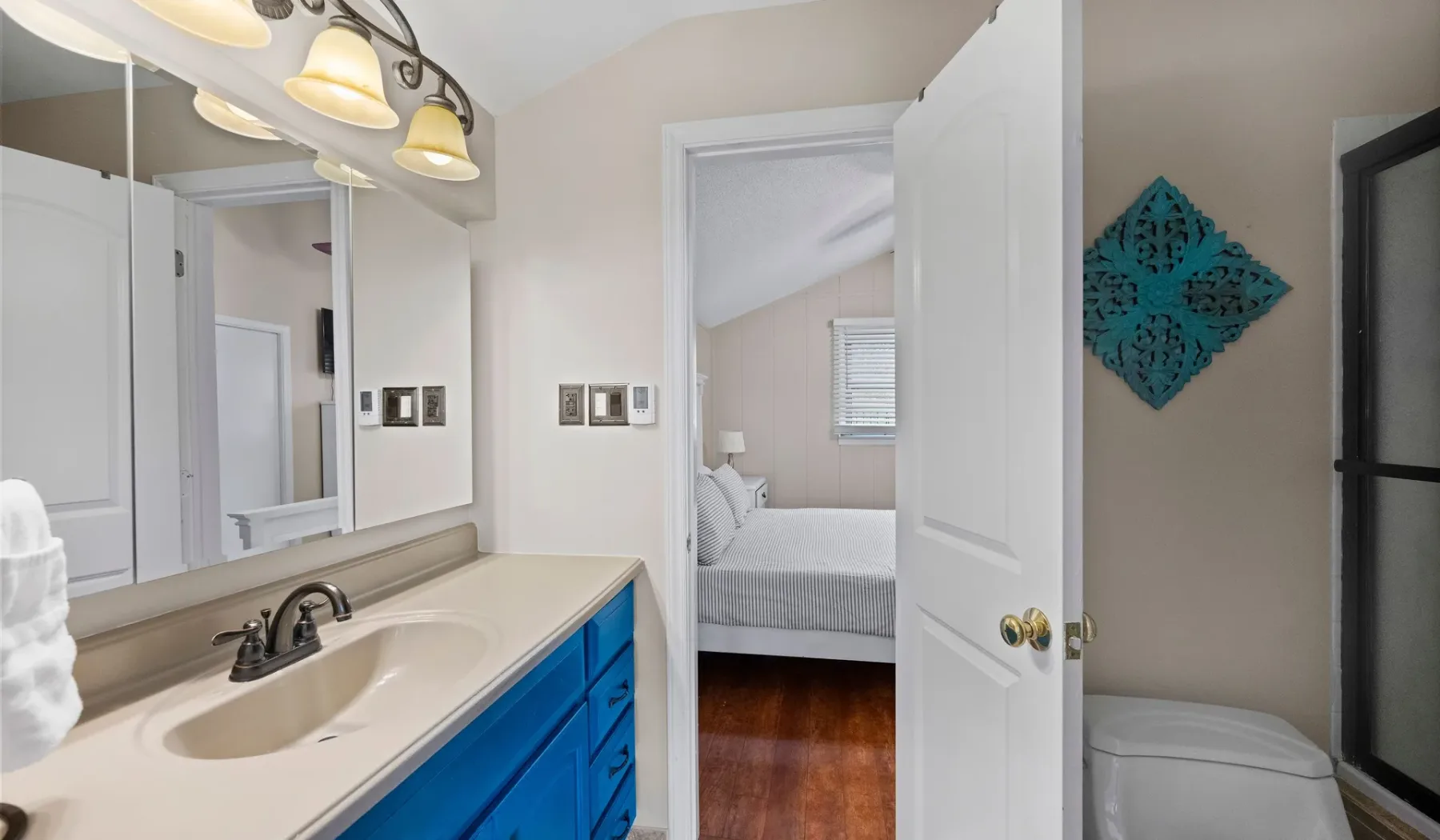 A bathroom vanity with a sink opens onto a bedroom through a doorway.