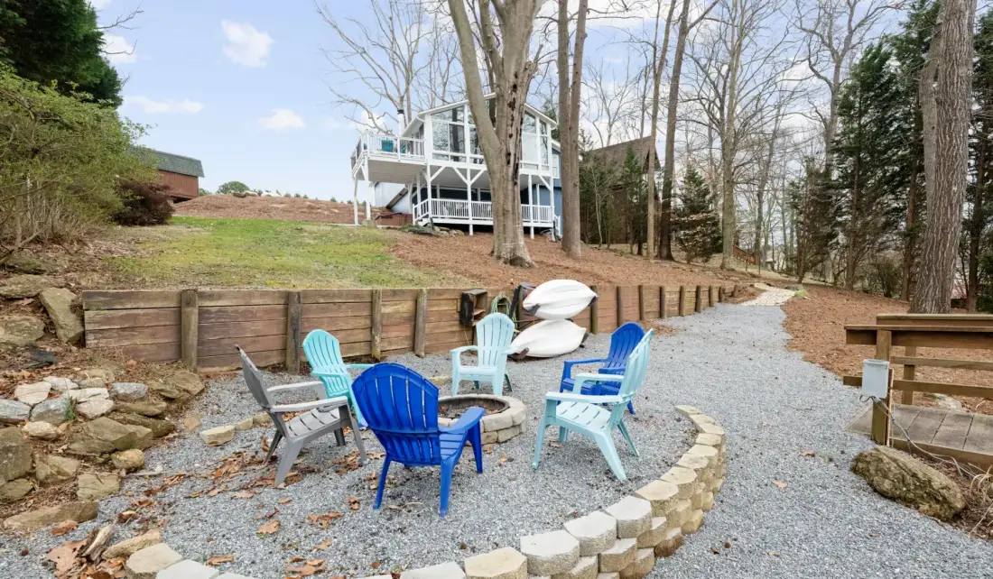 A gravel seating area with colorful chairs sits beside a low stone border.