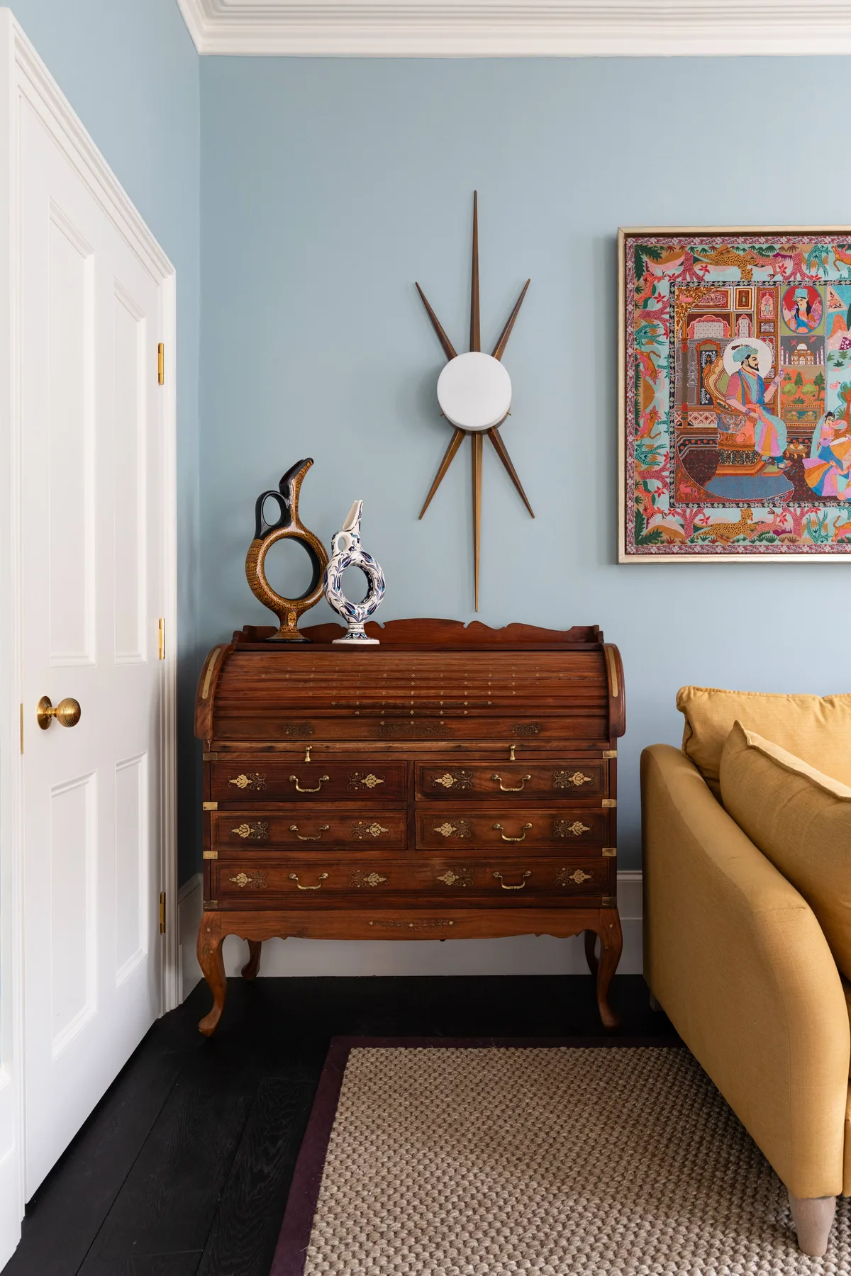 Una habitación amueblada con un baúl de madera, arte mural y asientos.