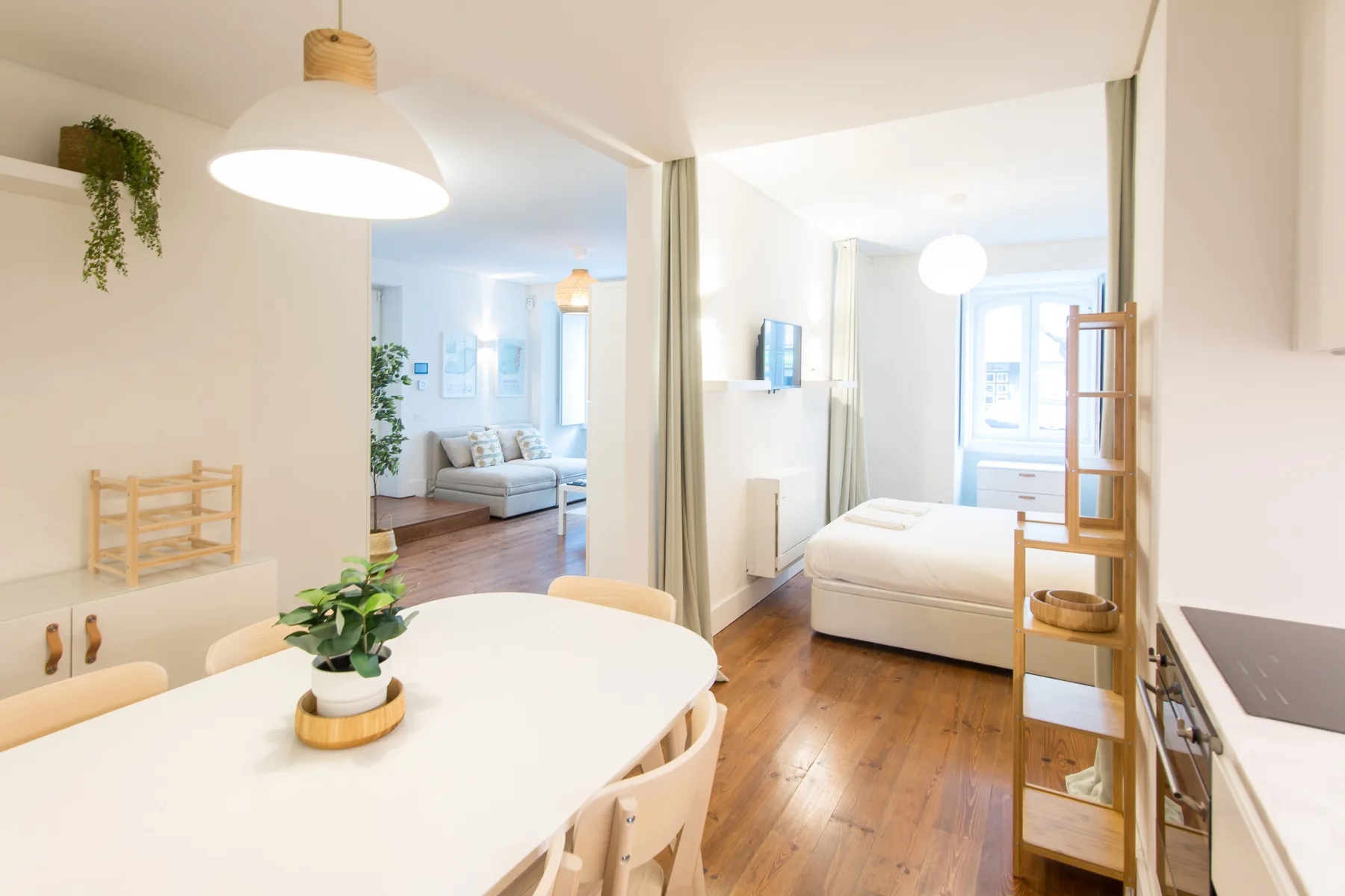 A bright open-plan apartment interior with a dining table and bed.