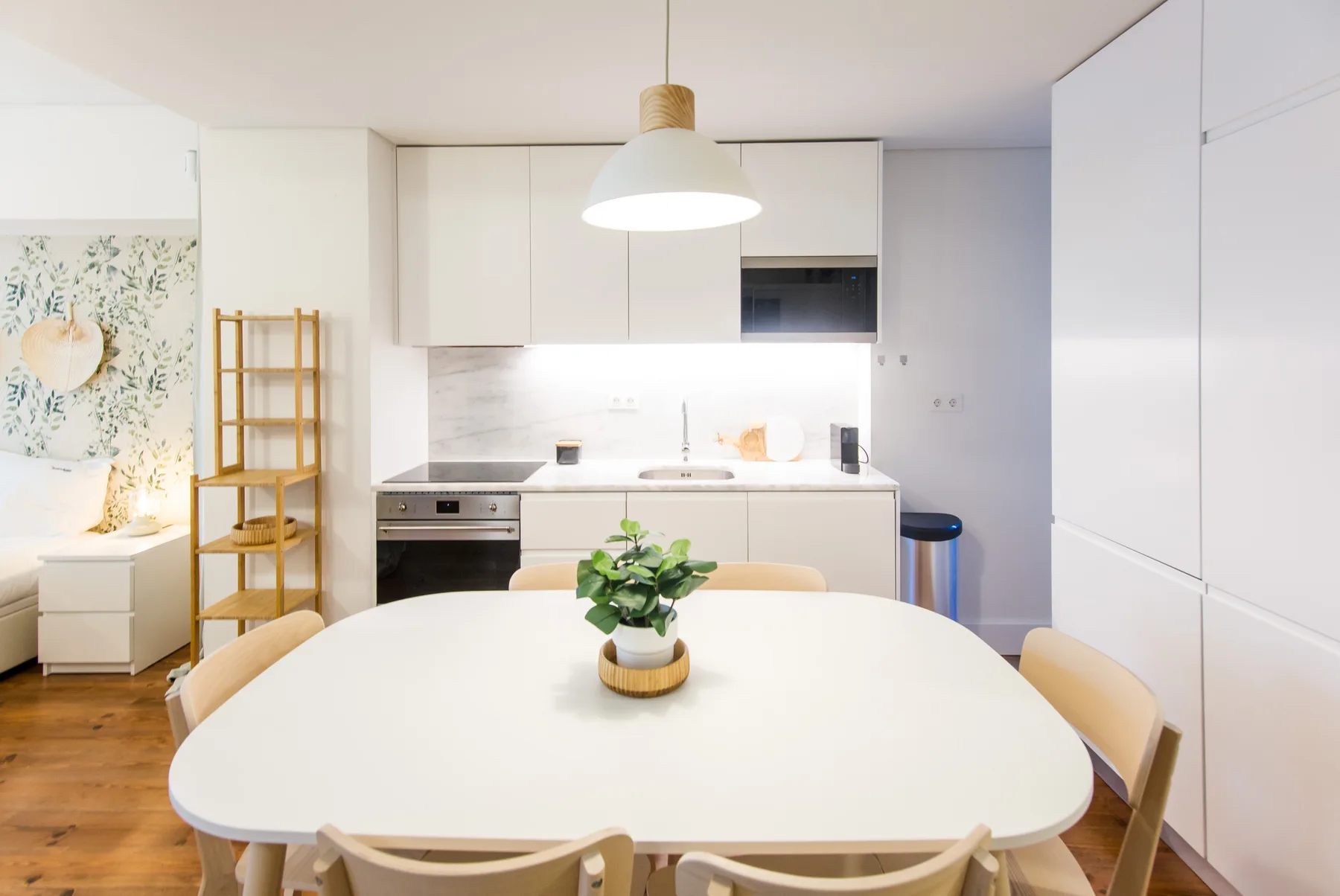 A bright dining area with a large table beside a compact kitchen.