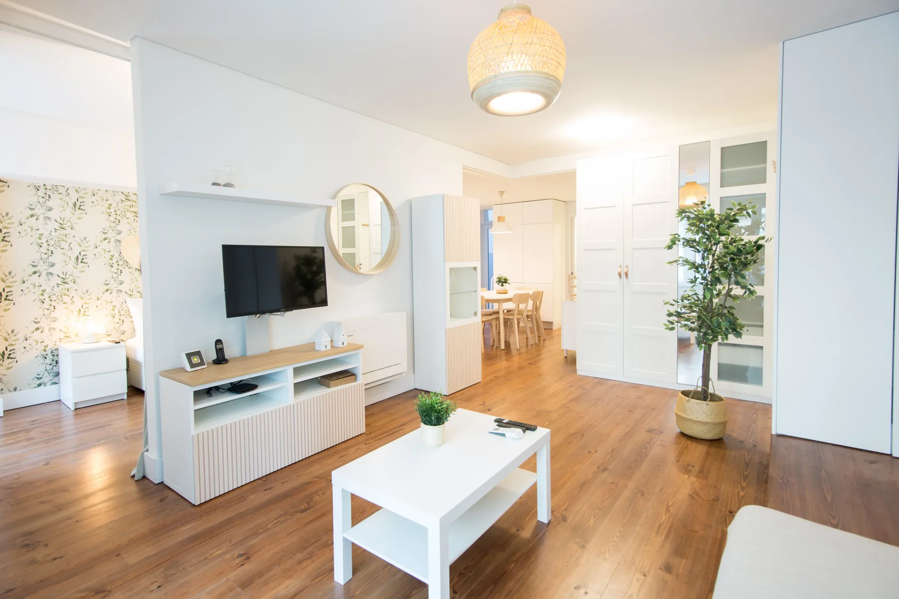A bright living room with a television and a white coffee table.