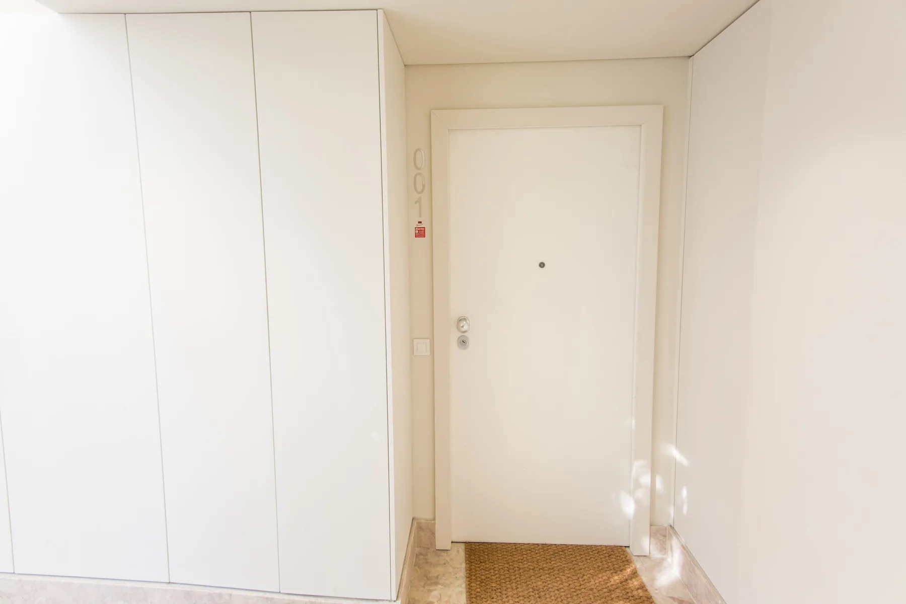 An apartment entryway with a white door and built-in cabinets.
