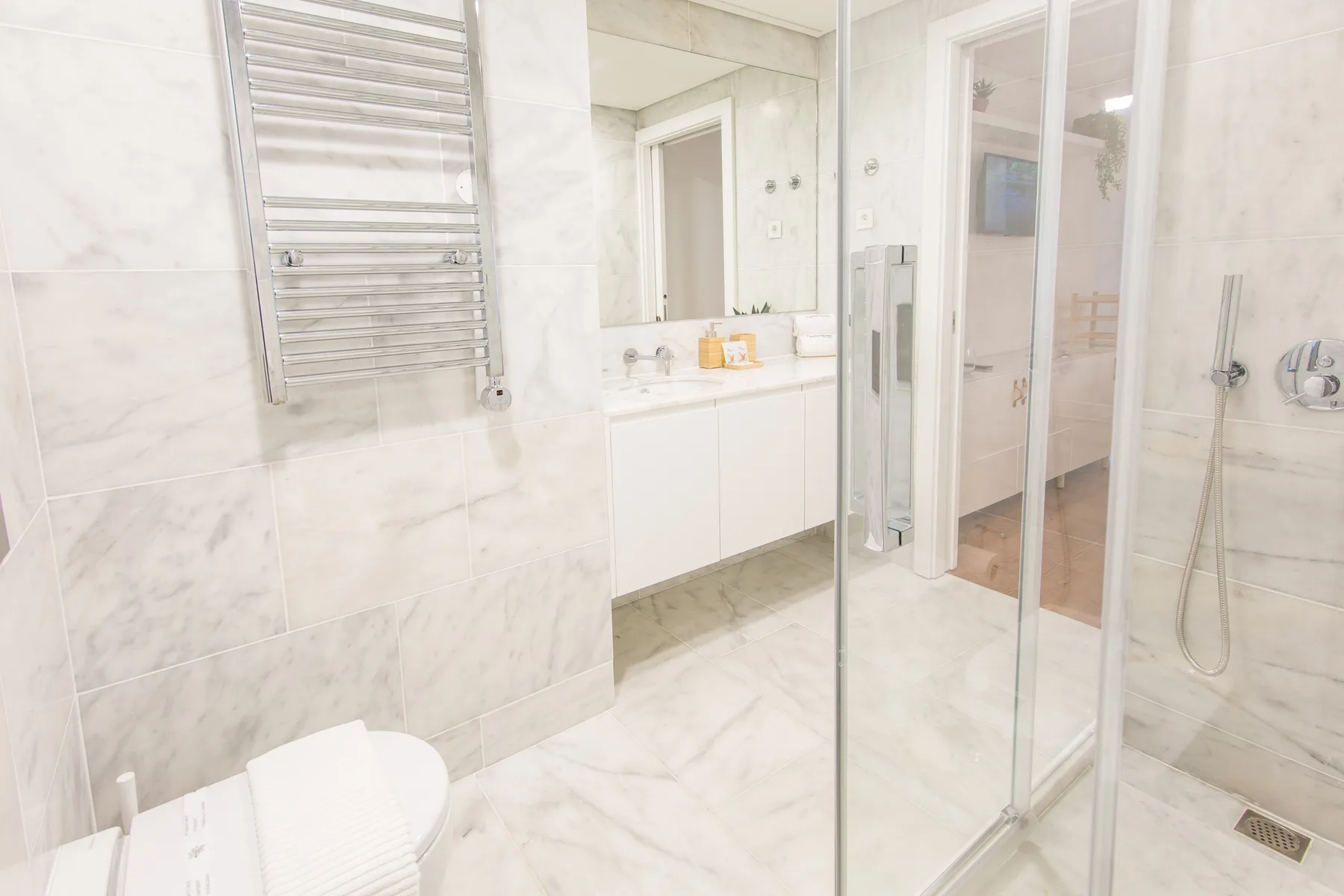A bright bathroom with a glass shower and a sink beneath a mirror.