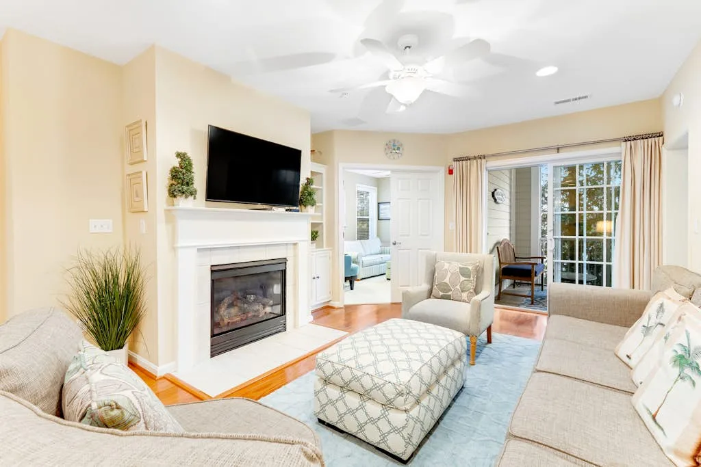 A bright living room with a fireplace, seating, and large glass doors.