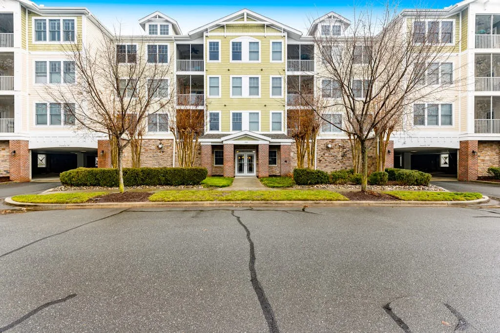 An apartment building facade with white trim and a landscaped entrance.