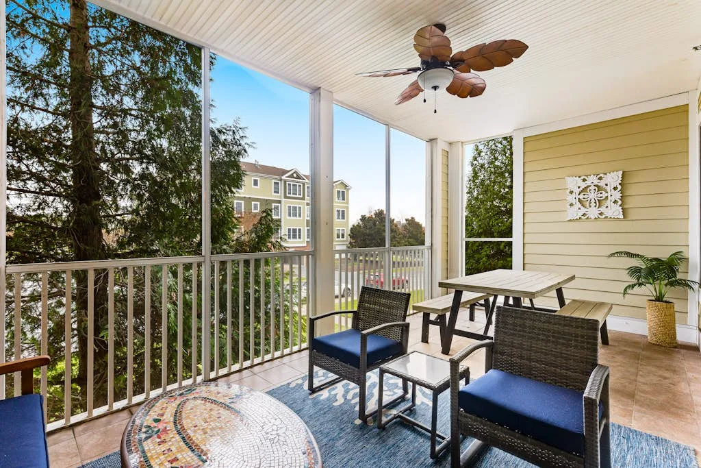 A bright enclosed patio with seating, a table, and large windows.