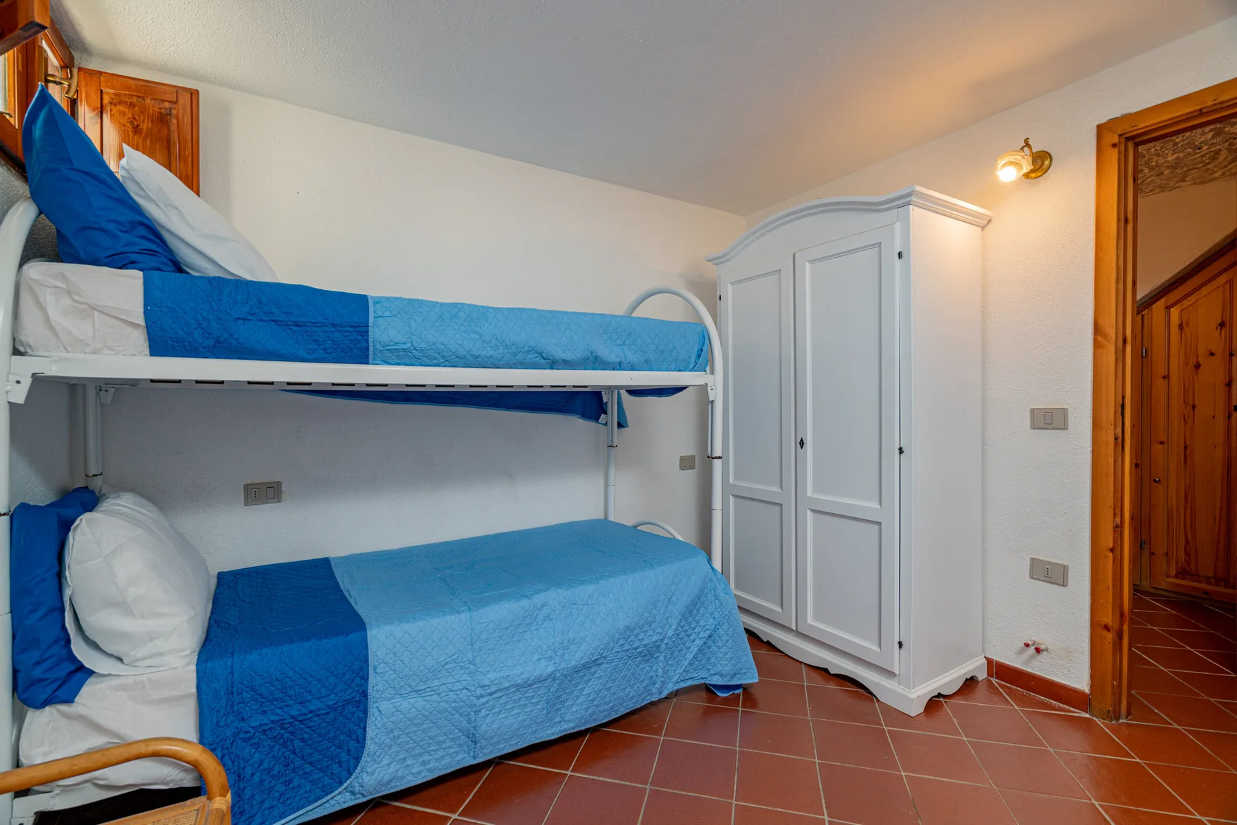 Un dormitorio con dos camas litera y un armario blanco.