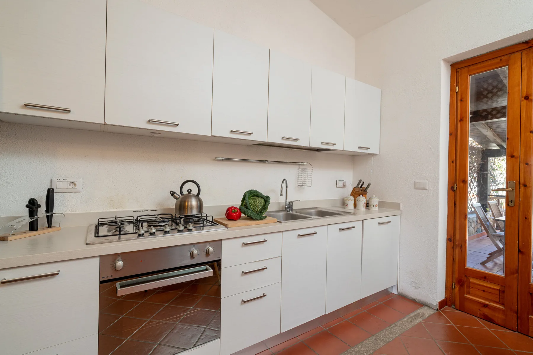 Una cocina luminosa con gabinetes blancos, una estufa y un fregadero.