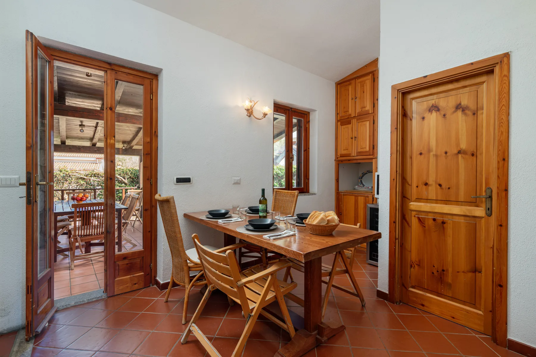 Comedor con mesa y sillas de madera junto a unas puertas de cristal.