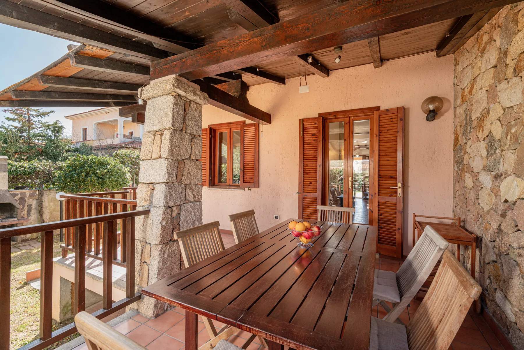 Comedor exterior cubierto con una mesa larga de madera y sillas.