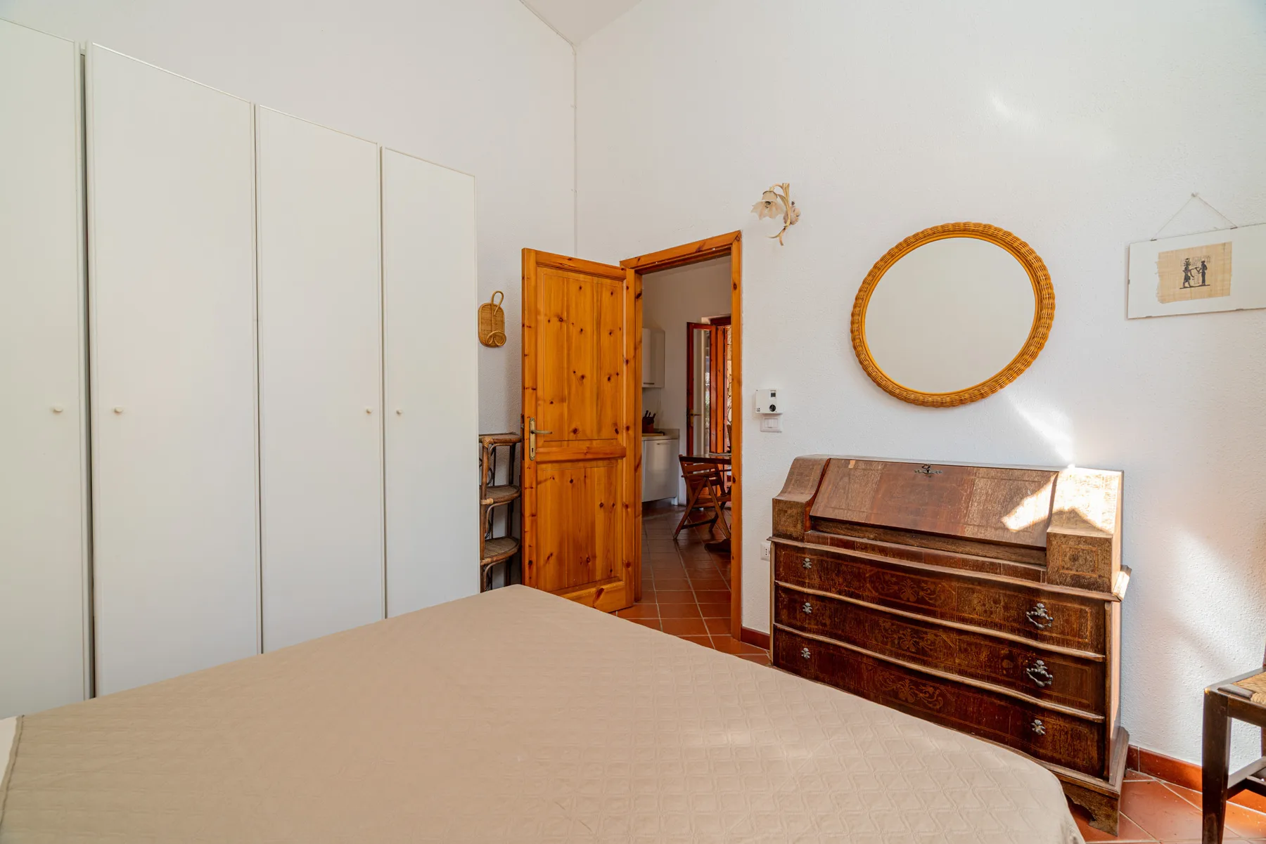 Un dormitorio con una cama, una cómoda de madera y una puerta abierta.