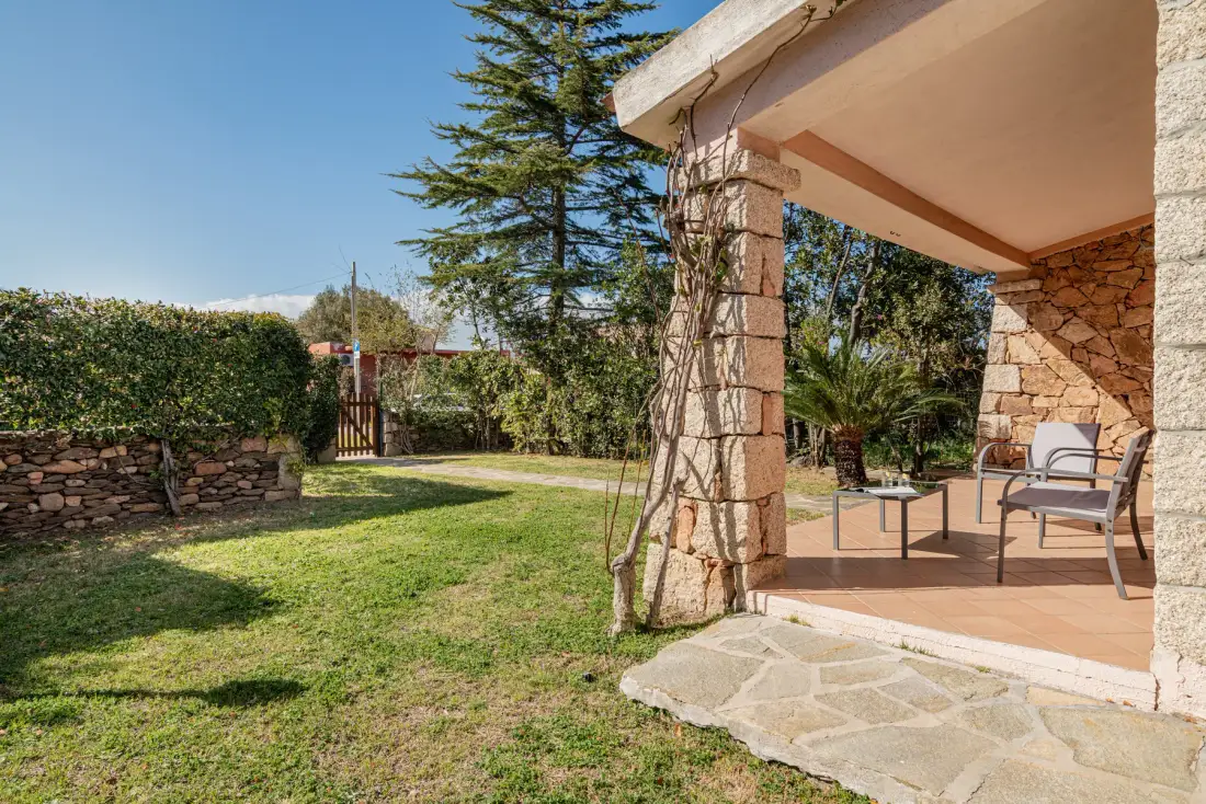 Un jardín con césped junto a un patio cubierto con asientos al aire libre.