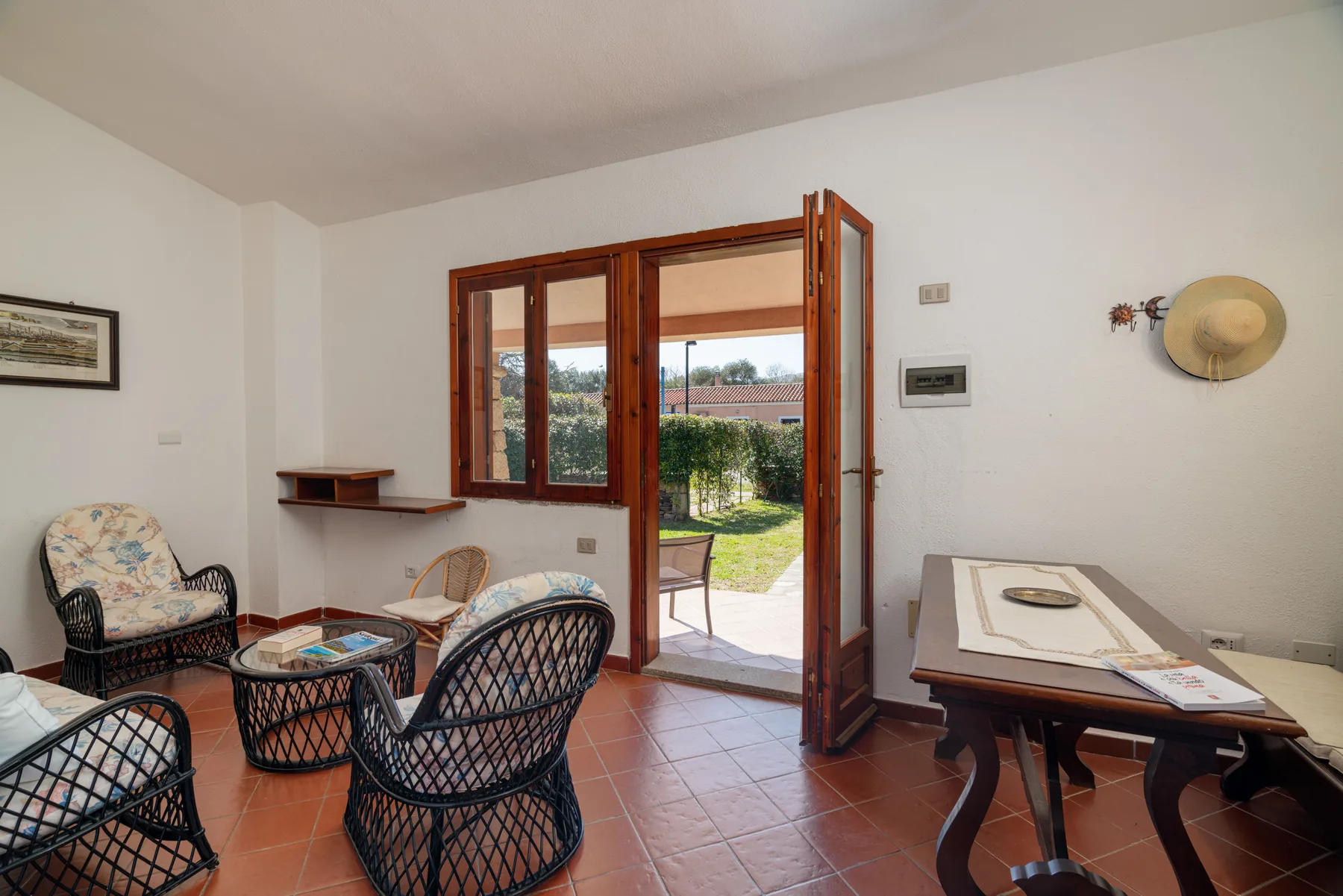 Una luminosa sala de estar y comedor se abre al jardín mediante grandes puertas de madera.