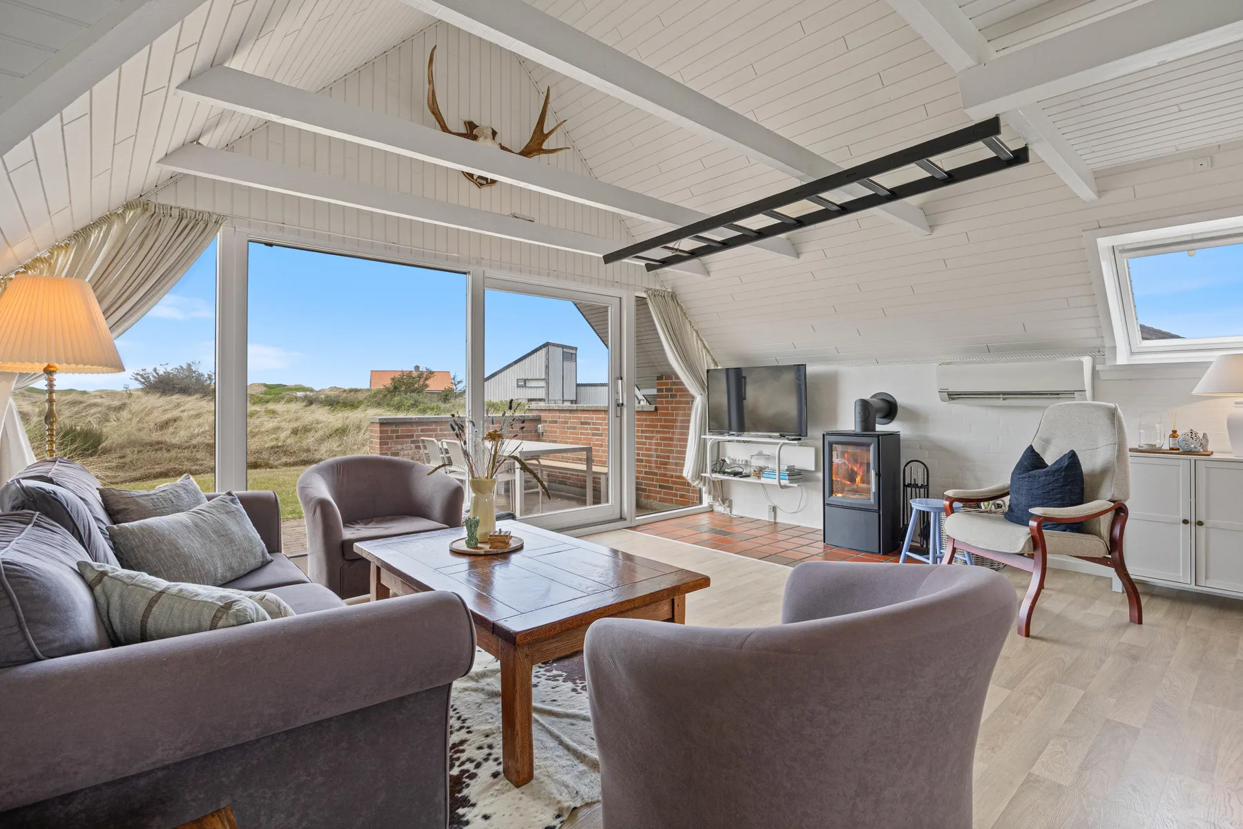 A bright living room with seating around a coffee table and a television.