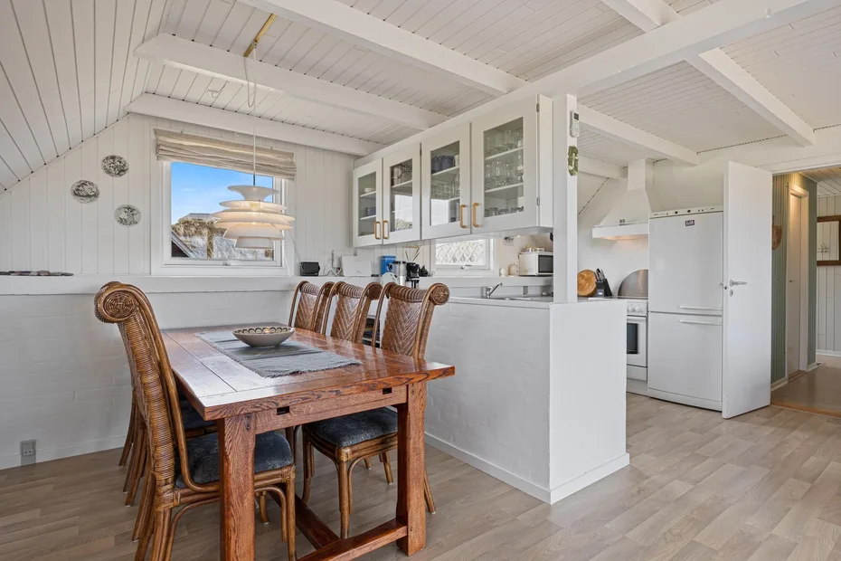 A bright kitchen and dining area with a wooden table and white cabinetry.