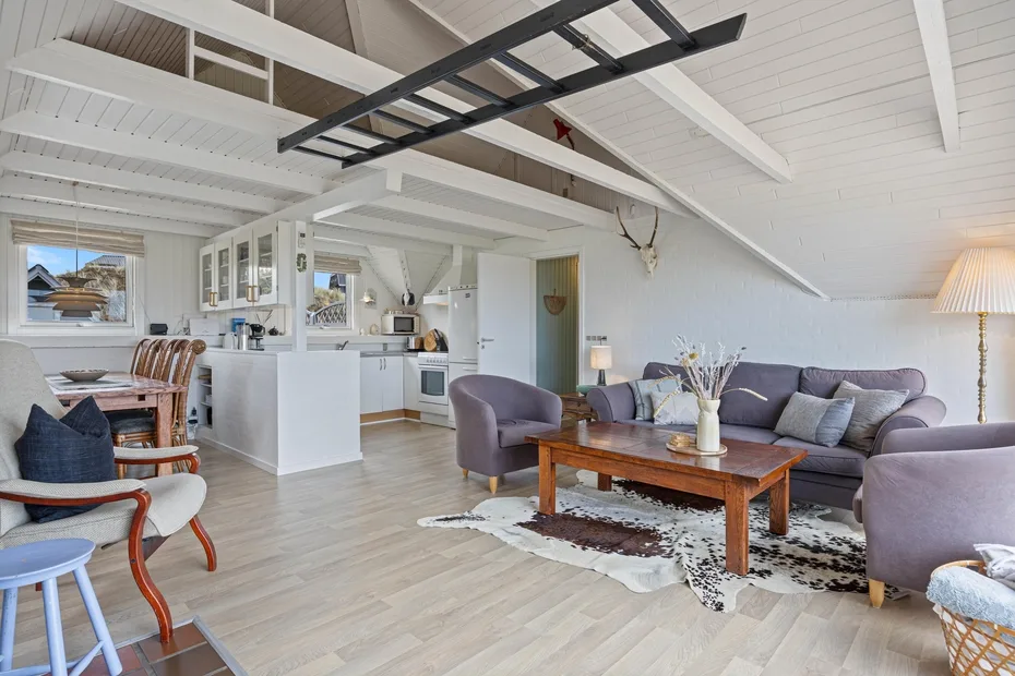 An open-plan living room and kitchen with seating and a wooden coffee table.
