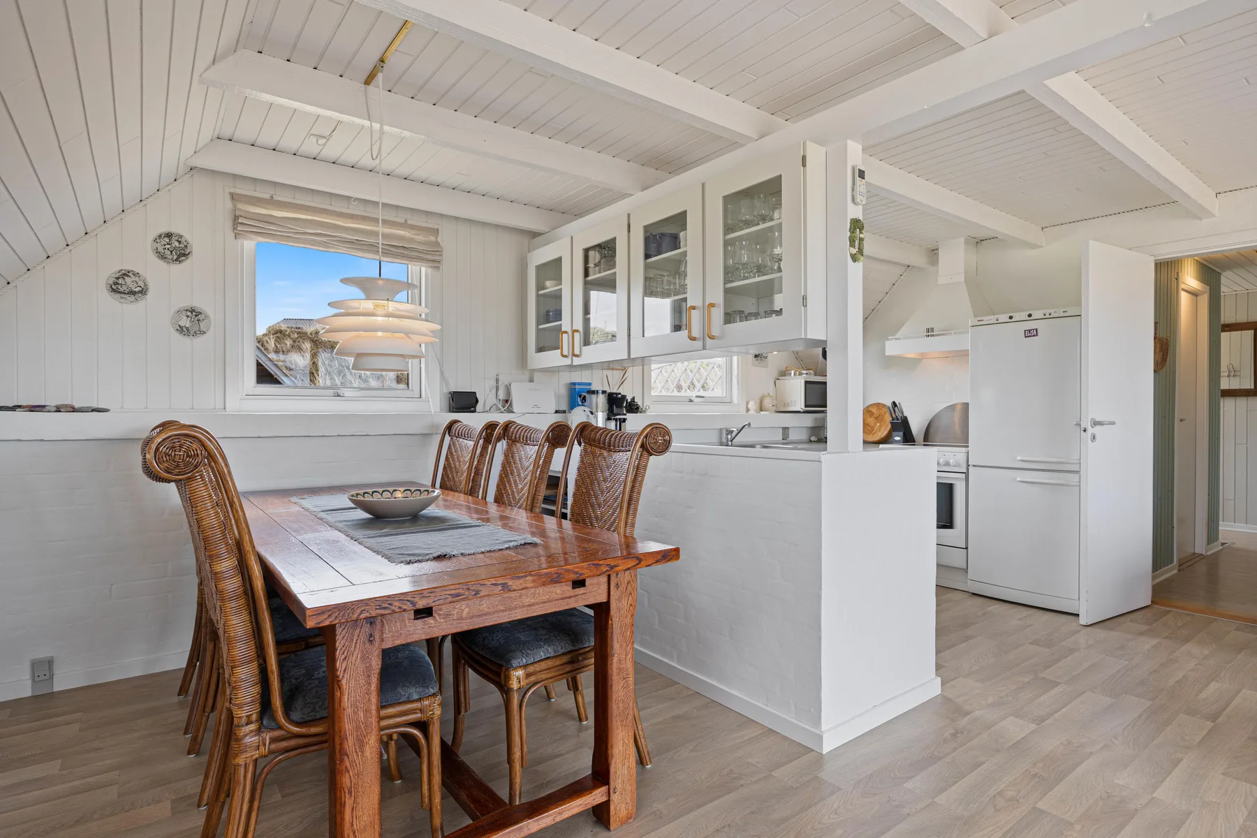 A dining area with a wooden table beside an open kitchen.