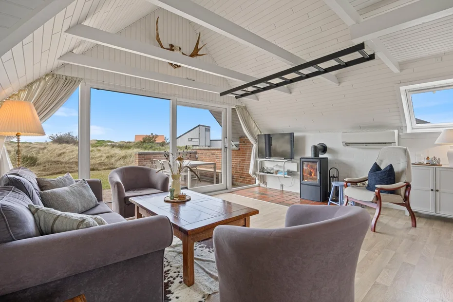 A bright living room with seating, a coffee table, and large windows.