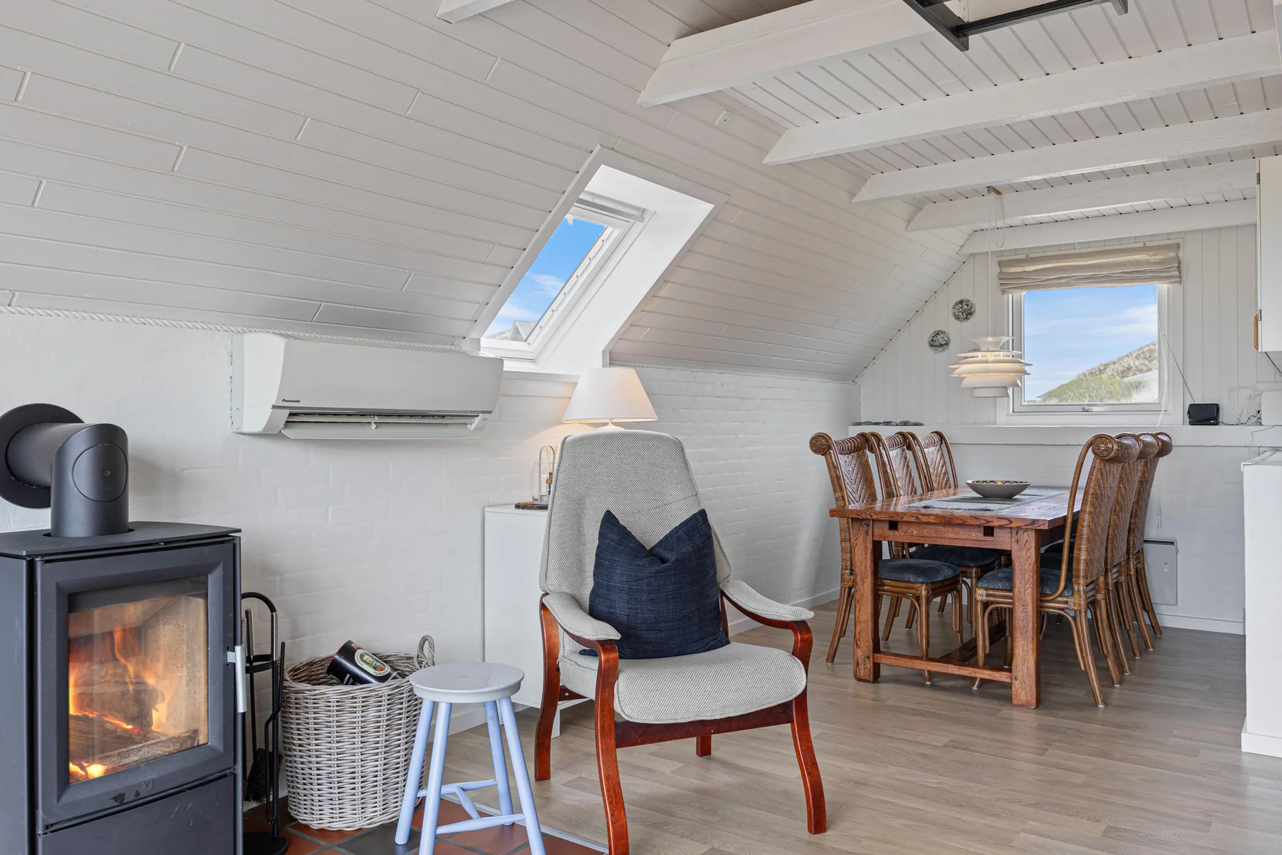 A bright dining and sitting area with a wood-burning stove and skylight.