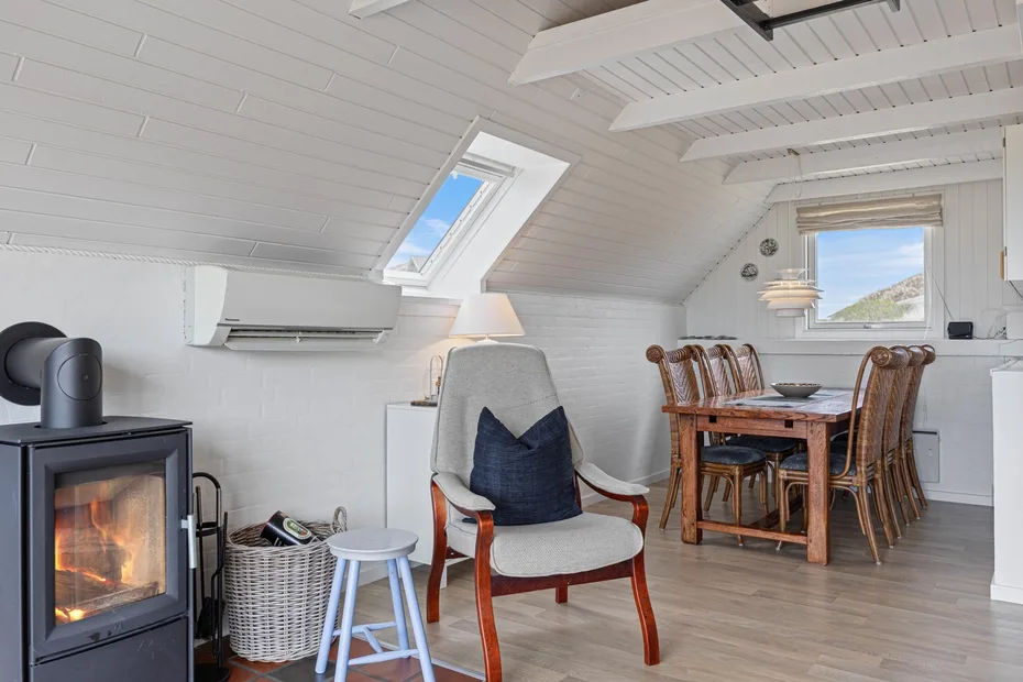 A bright loft sitting and dining area features a chair, wooden table, and skylight.