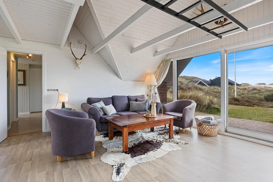 A bright living room with seating around a wooden coffee table and large windows.